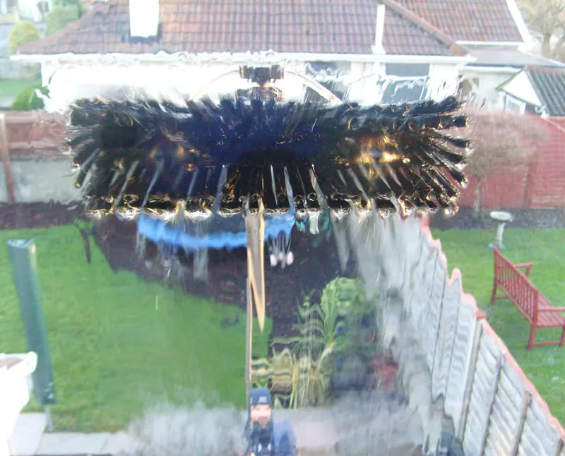 Water-fed pole brush cleaning a window with a back garden beyond
