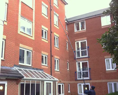 Window cleaner working beside a tall brick apartment block